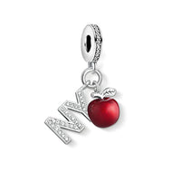 Silver charm with ’NY’ and a red apple.