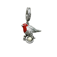 Silver bird charm with red head and nest.