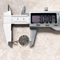 Round silver ring with colorful stones being measured.