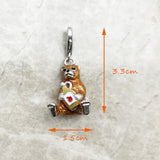 Enamel bear charm holding a heart-adorned jug.