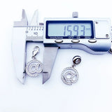 Silver ’@’ symbol charms being measured.