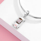Silver car charm with pink accents.
