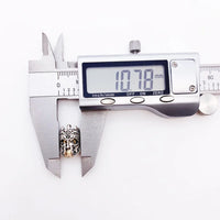 Silver and gold decorative bead being measured.
