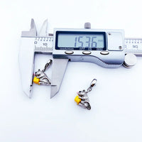 Silver-colored squirrel pendant with yellow object being measured.
