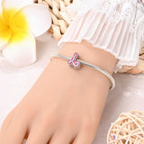 Silver charm bracelet with pink letter ’J’.