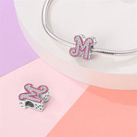 Letter ’M’ charm with pink trim and embedded crystals.