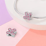 Letter ’M’ charm with pink trim and embedded crystals.