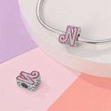 Silver letter ’N’ charm with pink trim and embedded crystals.