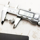 Digital caliper measuring a baby carriage charm.