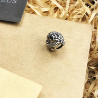 Silver frog charm with black stones.