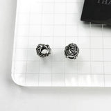 Two silver lion head beads.