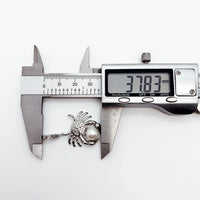 Crab-shaped pearl pendant being measured.