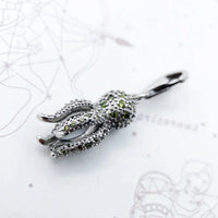 Silver octopus pendant with green accents.