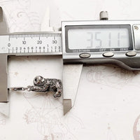 Silver sloth pendant being measured.