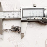 Silver sloth pendant being measured.