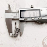 Silver sloth charm being measured.